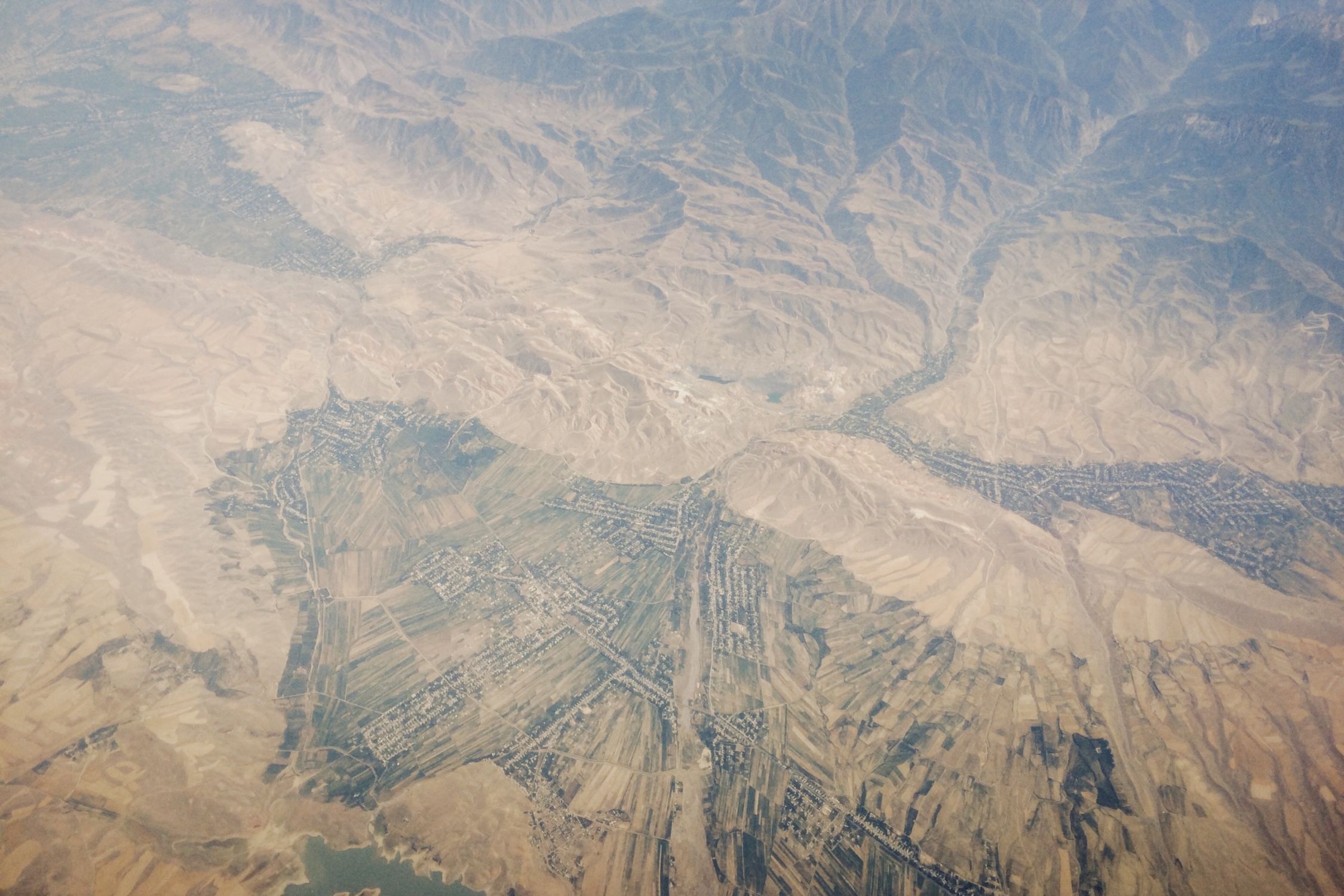 Wide highland valley with dry brown mountains stretching to the horizon under bright sky